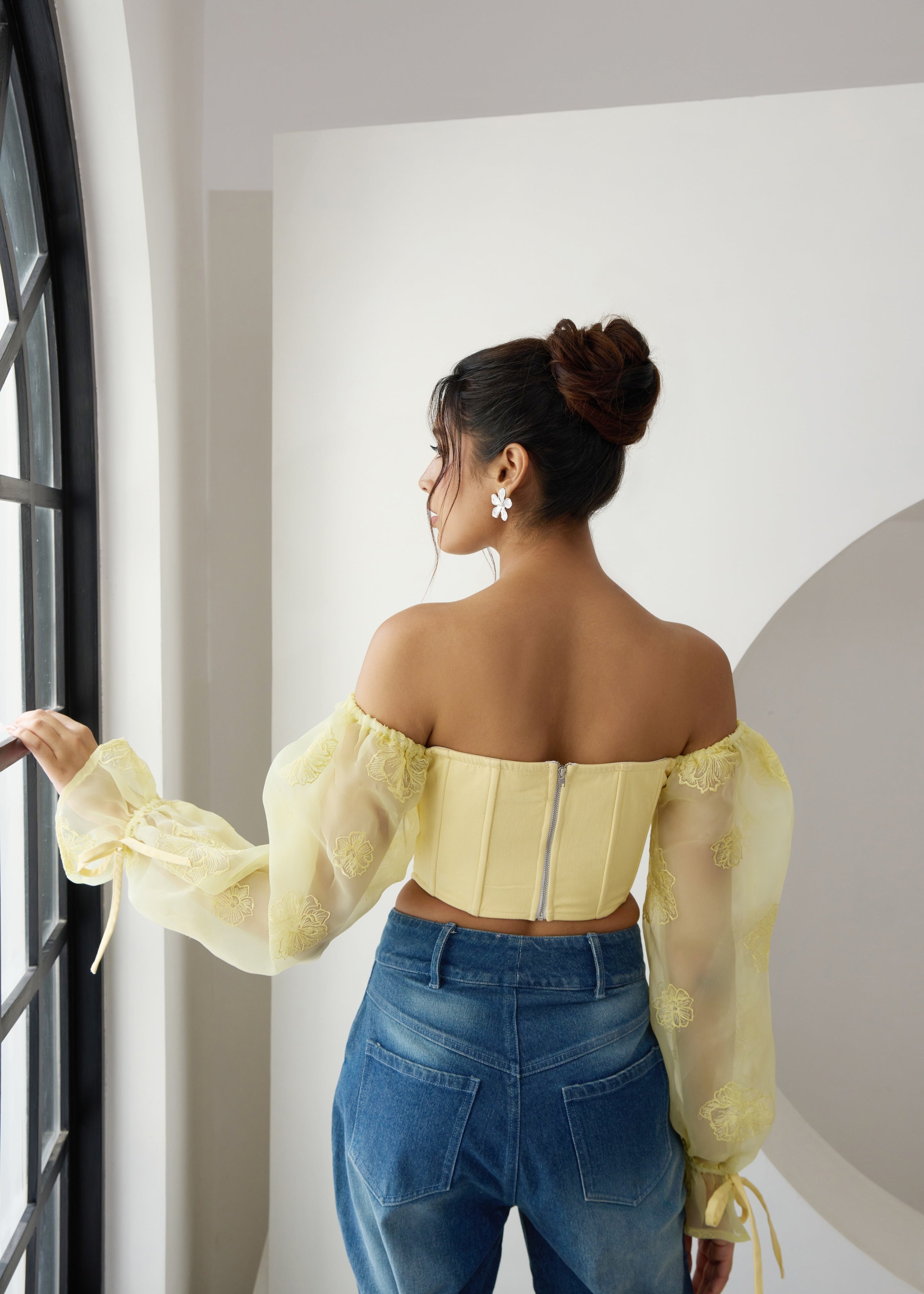 A yellow corset top with embroidered details and organza sleeves.