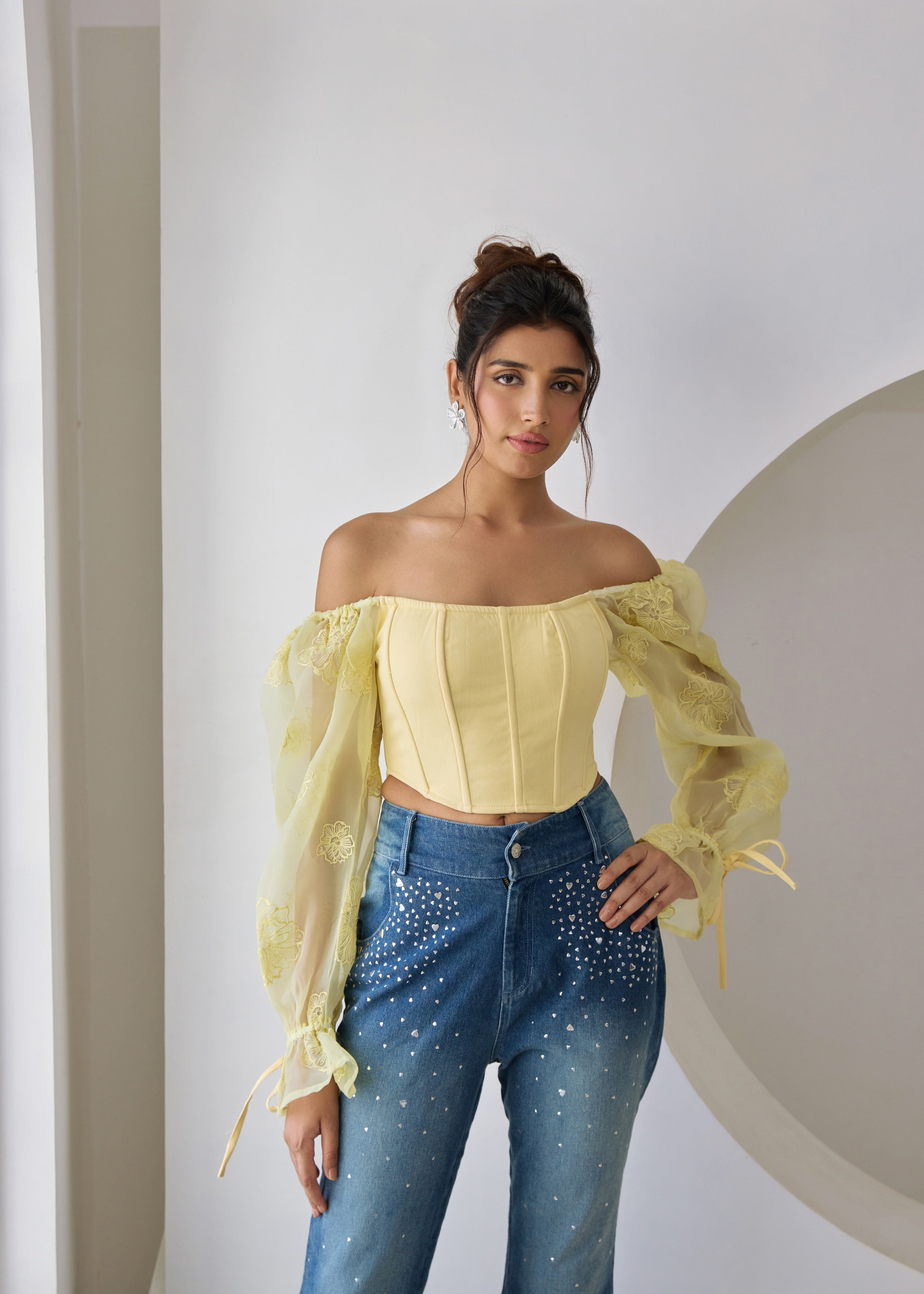 A yellow corset top with embroidered details and organza sleeves.