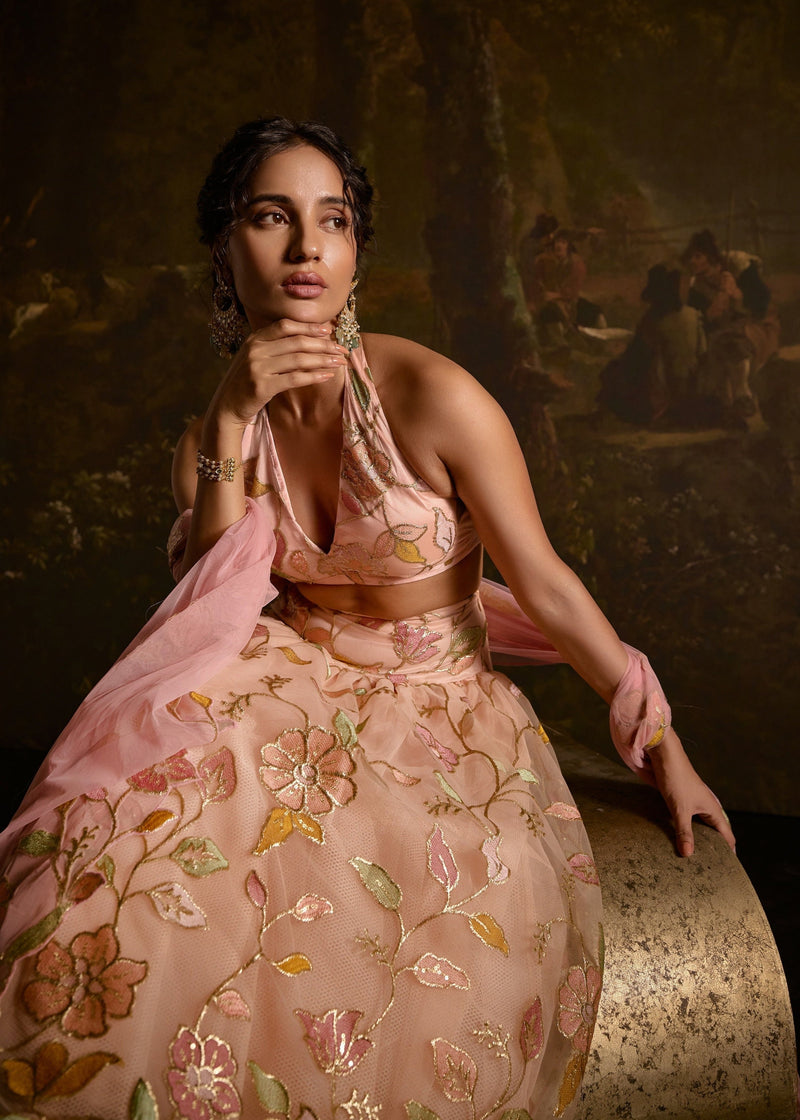 "Adishri Peach Halter-Neck Embroidered Lehenga: Elegant peach lehenga with halter-neck design and intricate embroidery, perfect for a graceful appearance."