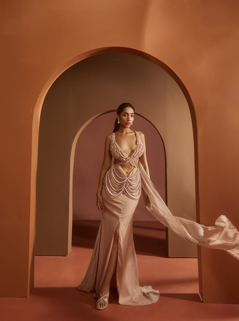 Chic woman in an Idika Nude Pink Pearl Criss-Cross Cutout Gown, exuding contemporary elegance