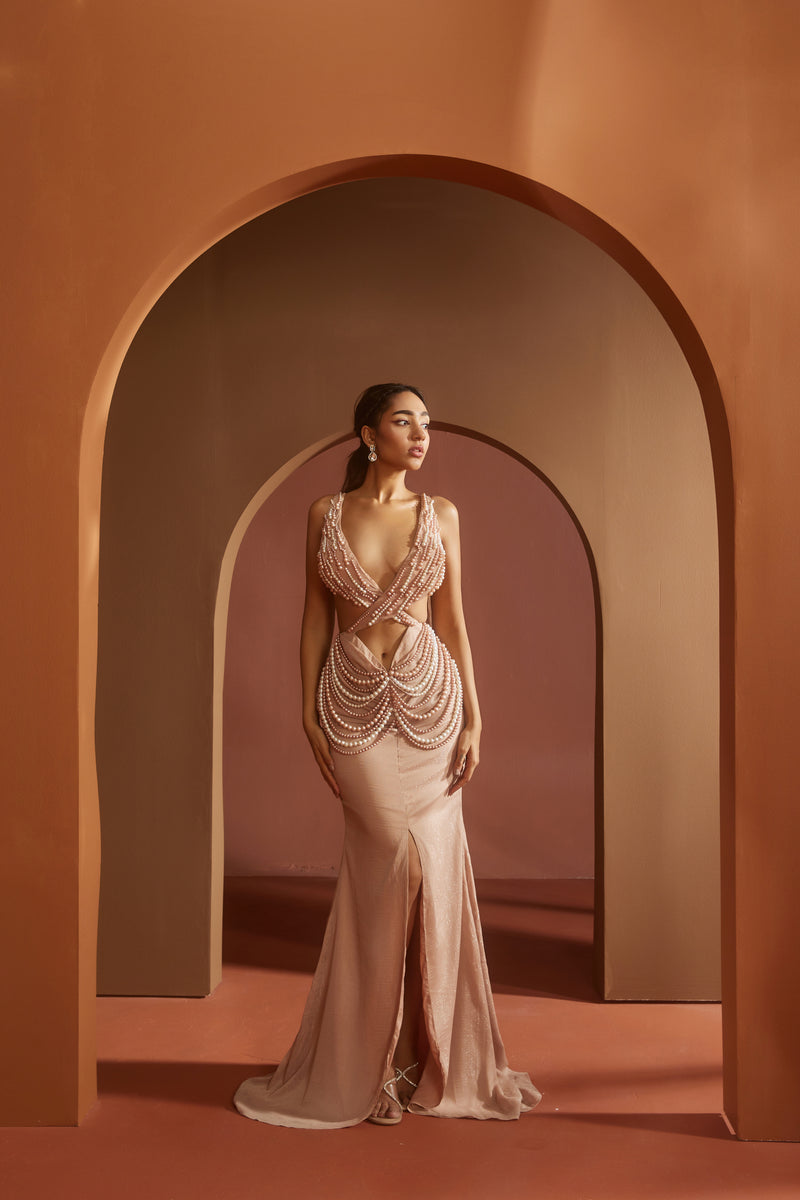 Chic woman in an Idika Nude Pink Pearl Criss-Cross Cutout Gown, exuding contemporary elegance