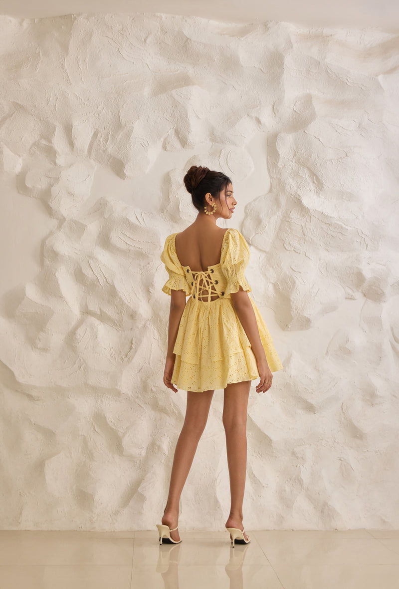 A vibrant Pixie yellow corset dress with Schiffli embroidery and puff sleeves.