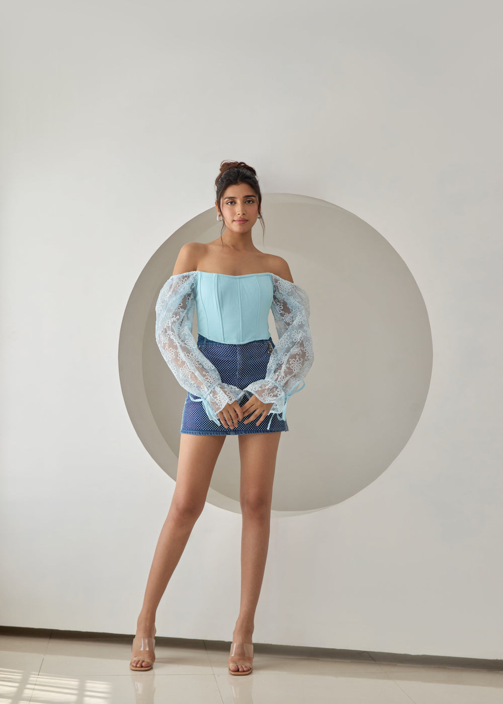 A baby blue corset top with embroidered details and organza sleeves.