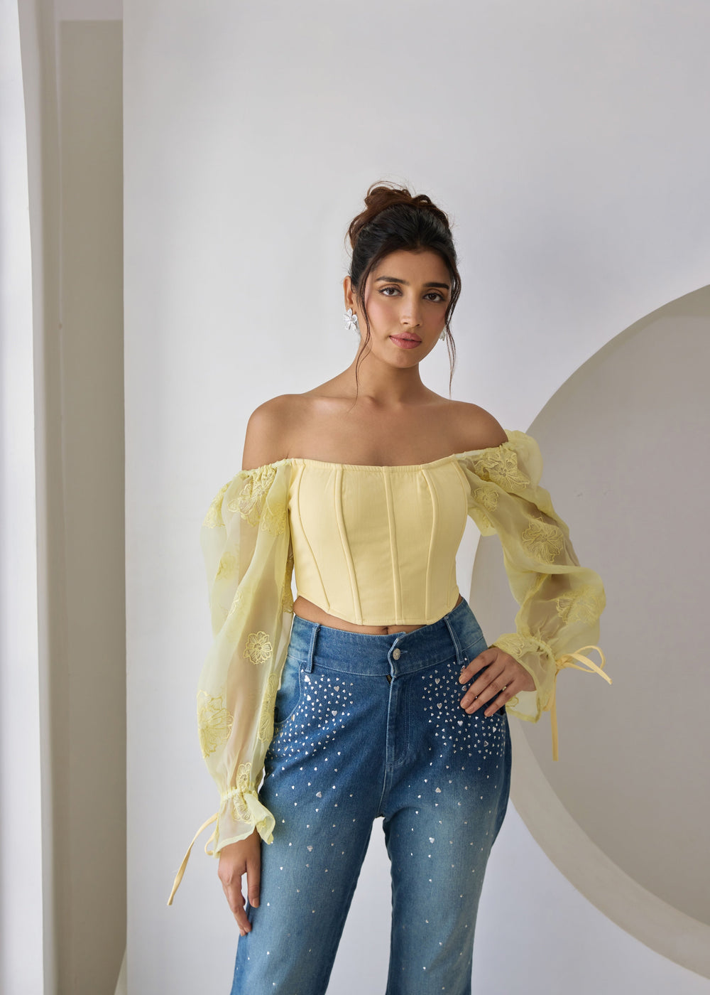 A yellow corset top with embroidered details and organza sleeves.