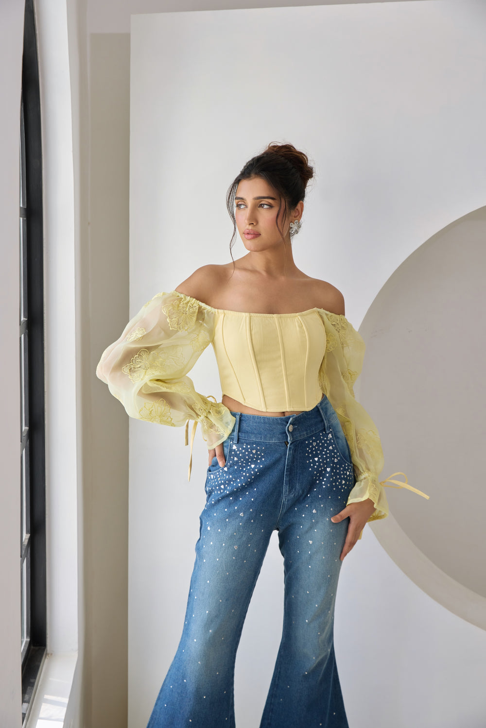 A yellow corset top with embroidered details and organza sleeves.